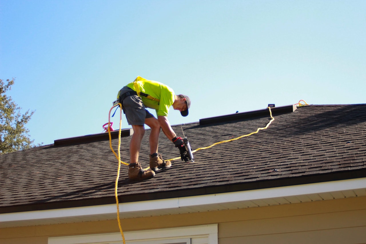 Roofer fastening new shingles with a nail gun