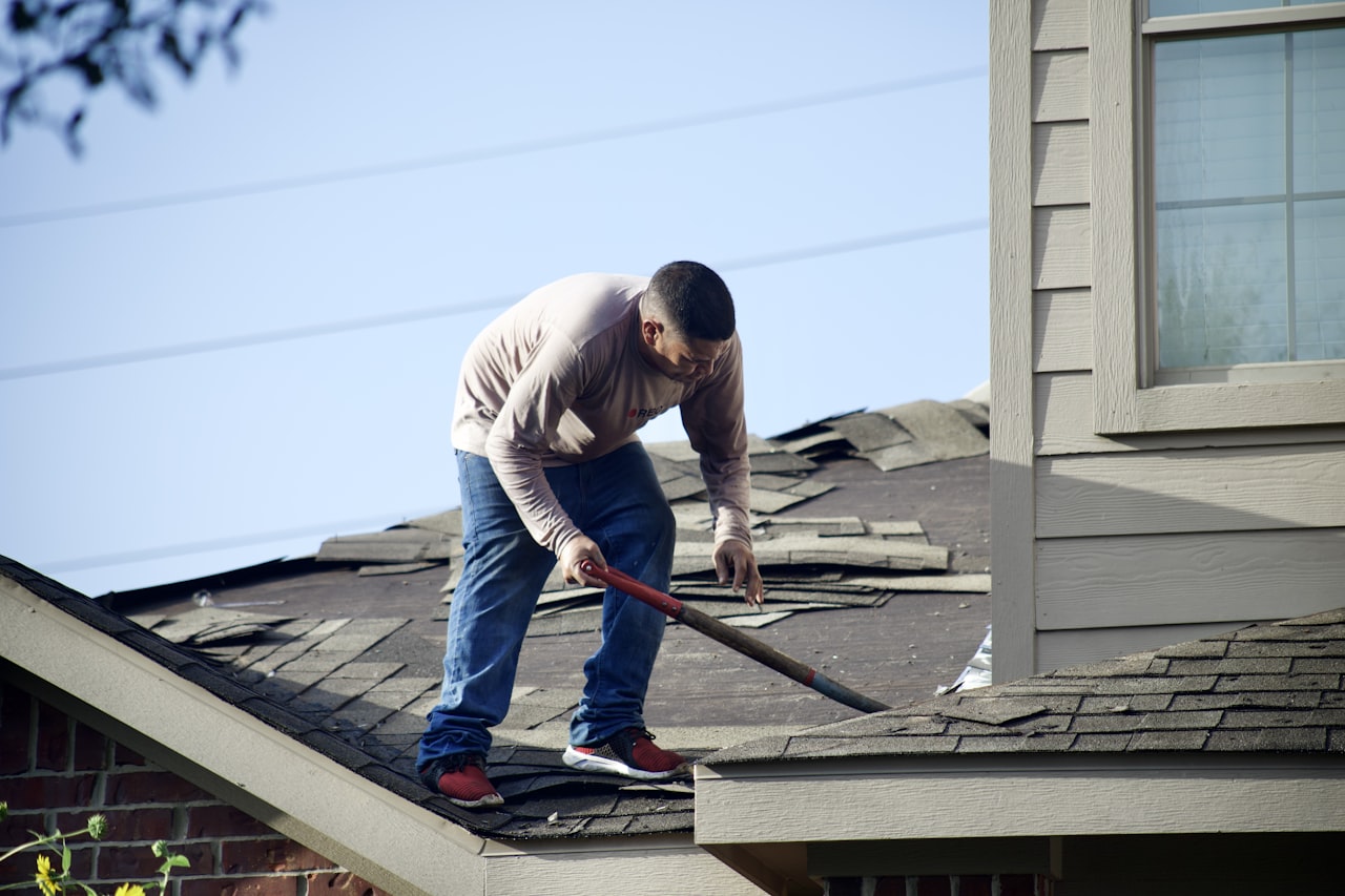 Roofer tearing off old shingles down to the deck